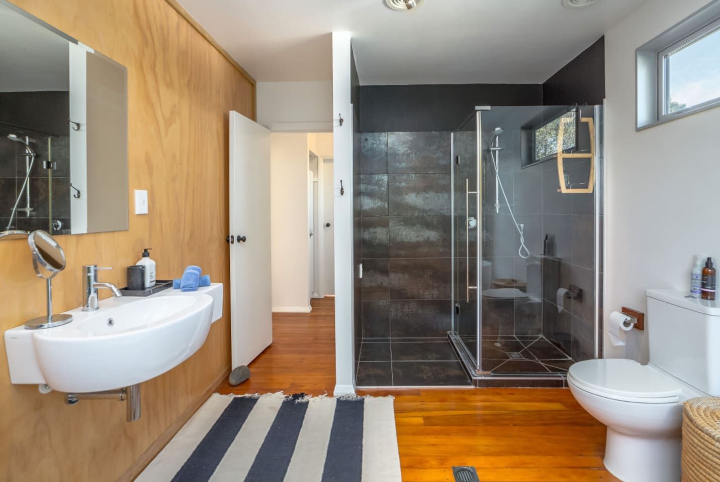 A modern bathroom with a large sink, mirror, and shower area.