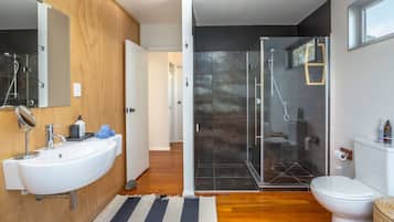 A modern bathroom with a large sink, mirror, and shower area.