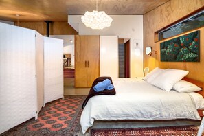 A bedroom with a bed, a wooden wardrobe, a hanging light fixture, and a painting on the wall. - Family Retreat, Martinborough (Martinborough)