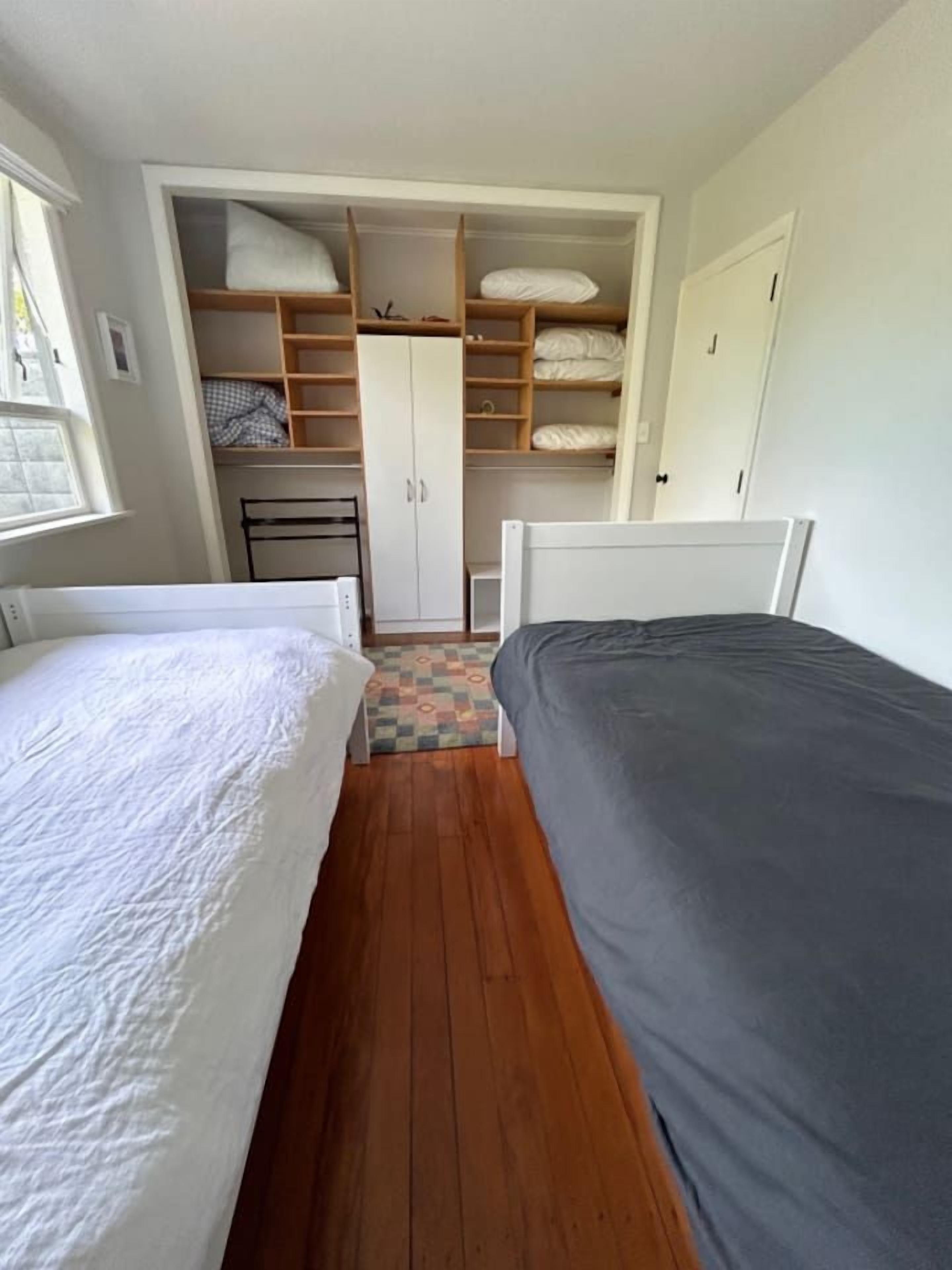 Ein Schlafzimmer mit zwei Betten, einem Kleiderschrank und einem kleinen Tisch.