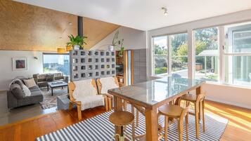 Un espace de vie moderne avec une table à manger en verre, des chaises en bois, un canapé gris et un tapis à rayures.