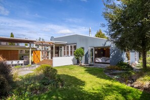A modern house with a covered patio, a separate garage, and a well-maintained garden.