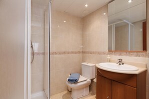 Un baño moderno con cabina de ducha de vidrio, un inodoro y un lavabo con espejo.