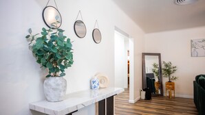 A hallway with a marble console table, a potted plant, and two mirrors on the wall. - The Yuma White Modern Pool/Pet friendly Home (Yuma)