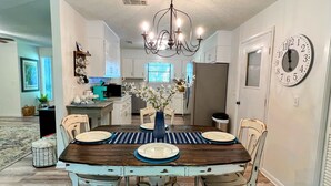 A dining area with a wooden table, chairs, a bench, a chandelier, and a clock on the wall. - Paradise is waiting for you! Minutes away from St. Simons, Jekyll, Golf & FLETC! (Brunswick)