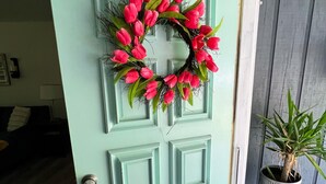 A teal door with a wreath of pink flowers and a potted plant beside it. - Paradise is waiting for you! Minutes away from St. Simons, Jekyll, Golf & FLETC! (Brunswick)