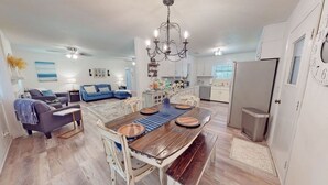 A spacious living area with a dining table, sofas, and a kitchen in the background. - Paradise is waiting for you! Minutes away from St. Simons, Jekyll, Golf & FLETC! (Brunswick)