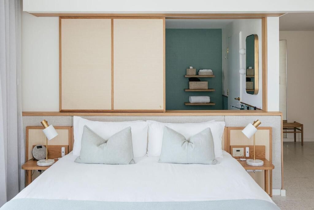 Ein Hotelzimmer mit einem großen Bett, zwei Nachttischen mit Lampen, einem Kleiderschrank und einem Spiegel.