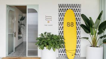 Un interior moderno con un símbolo de número con forma de tabla de surf, una planta en maceta y un diseño geométrico en la pared.