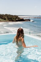 A person in a swimming pool with a view of the ocean and beach.