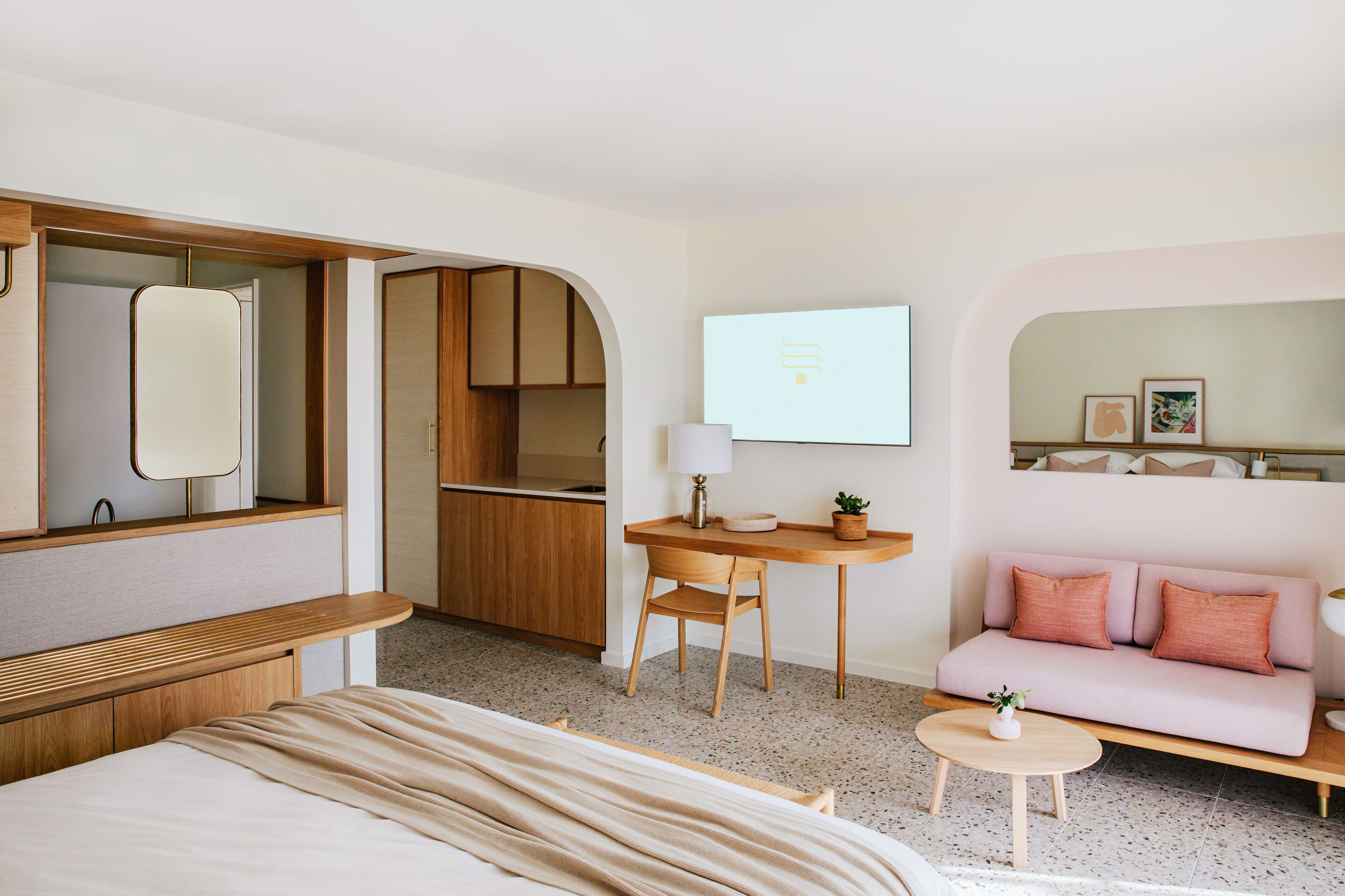 Et moderne hotelværelse med seng, sofa, skrivebord og tekøkken.