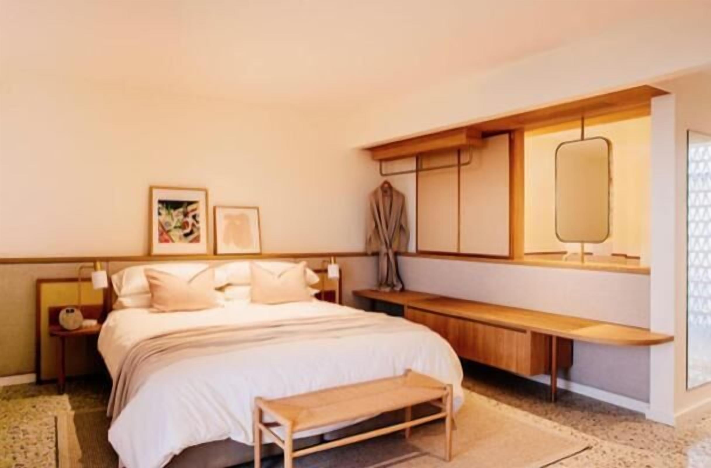 Una habitació d'hotel moderna amb un llit gran, una panxa, una taula de nit i un televisor fixat a la paret.