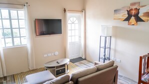 Una sala de estar con sofá, televisión, puerta y ventana.