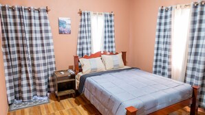 Un dormitorio con cama, mesita de noche y cortinas.