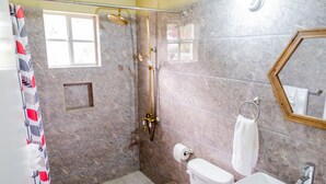 Un baño con ducha, inodoro, lavamanos y ventana.