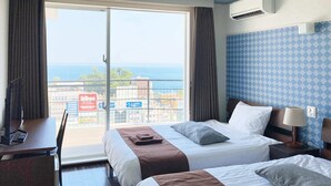 Habitació d'hotel amb dos llits, una taula de treball, una cadira i vista al mar.