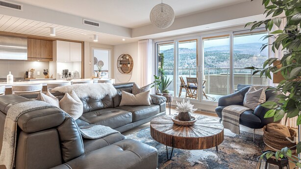 A modern living room with a grey sofa, a round coffee table, and a view of a balcony. - ❤️ Mountain View and Lake Access - Mont-Tremblant (Mont-Tremblant)