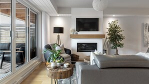 A modern living room with a sofa, a coffee table, a fireplace, and a television. - ❤️ Mountain View and Lake Access - Mont-Tremblant (Mont-Tremblant)