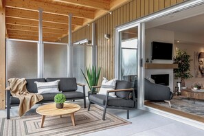A modern living room with a sofa, armchairs, a coffee table, and a TV.