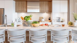 A modern kitchen with wooden cabinets, a central island with bar stools, and various kitchen items. - ❤️ Mountain View and Lake Access - Mont-Tremblant (Mont-Tremblant)