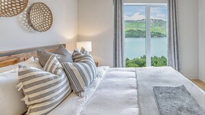 A bedroom with a large bed, a view of a lake, and a window with curtains. - ❤️ Mountain View and Lake Access - Mont-Tremblant (Mont-Tremblant)