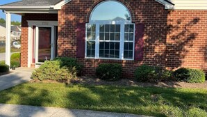 A two-story brick house with a large arched window and a garage door.