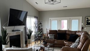 A living room with a fireplace, leather sofa, and a TV mounted on the wall.
