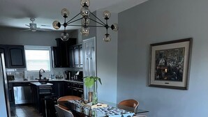 A modern kitchen with dark cabinets, stainless steel appliances, and a dining area with a table and chairs.