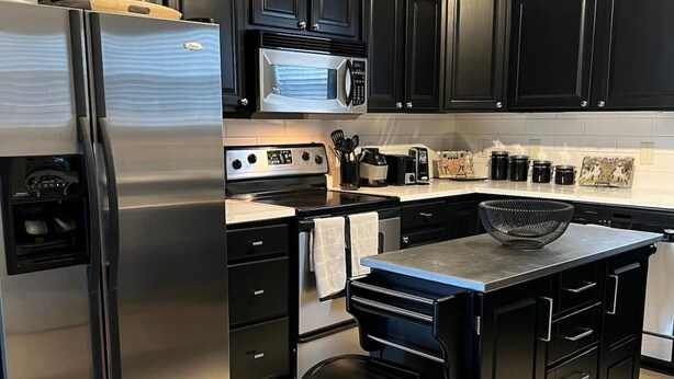 A modern kitchen with black cabinets, stainless steel appliances, and a central island.