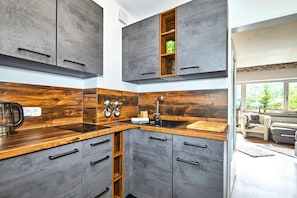 Een moderne keuken met grijze kastjes, een houten aanrechtblad en een inbouwplankje met een blik er op.