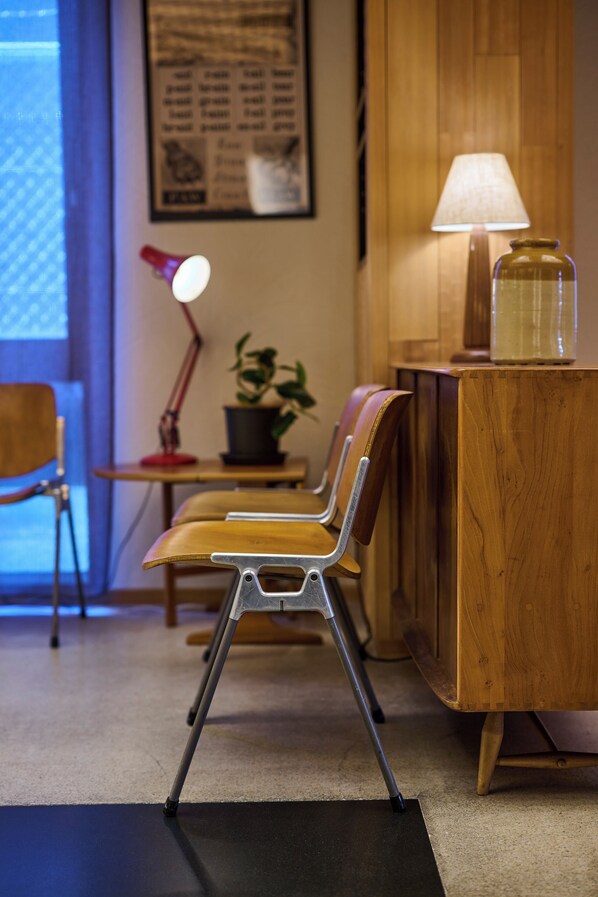 A wooden desk with a lamp, a potted plant, and a jar on it.