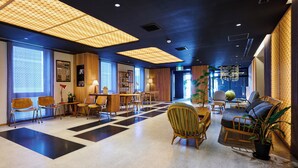 Un vestíbulo amplio con suelo de cuadros, muebles de madera y ventanas grandes.