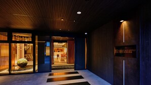 Una entrada de hotel moderna con techo de madera, un mostrador de recepción y un cartel que indica el nombre del hotel.