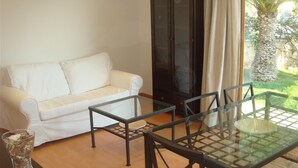 A white sofa, a glass-top table with chairs, and a glass cabinet. - Holiday Villa in Tarragona with Open Terrace, Garden & Wi-Fi (Tarragona)