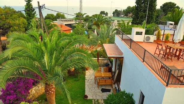 A residential property with a patio, outdoor seating, a stone pathway, and a view of the sea. - Holiday Villa in Tarragona with Open Terrace, Garden & Wi-Fi (Tarragona)