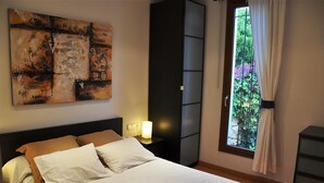 A bedroom with a bed, a nightstand, a wall art piece, a window with curtains, and a dresser. - Holiday Villa in Tarragona with Open Terrace, Garden & Wi-Fi (Tarragona)