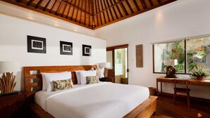 A spacious bedroom with a large bed, wooden headboard, and a desk with a chair. - Villa Perere9 by Nakula (Canggu)