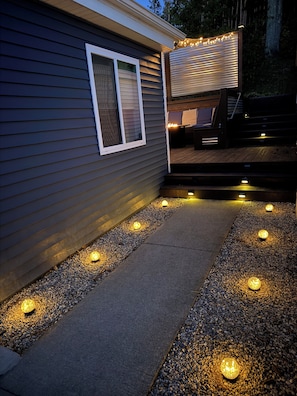 Una casa con un sendero iluminado, una ventana y una zona de terraza.