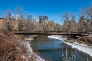 A river with a bridge, surrounded by trees and buildings in the background.