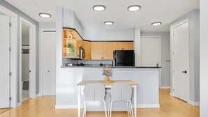 Eine moderne Küche mit Holzausstattung, einem schwarzen Kühlschrank und einer weißen Arbeitsplatte.