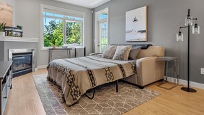 A modern bedroom with a bed, a fireplace, a desk, and a view of the outdoors. - River Downtown Condo, A/C, Underground Parking, Saddledome & Stampede (Calgary)