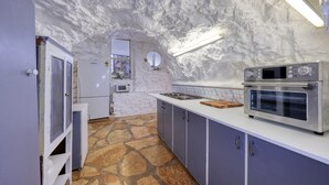 Une cuisine dotée d’un sol en pierre, de meubles blancs et d’appareils électroménagers en acier inoxydable.