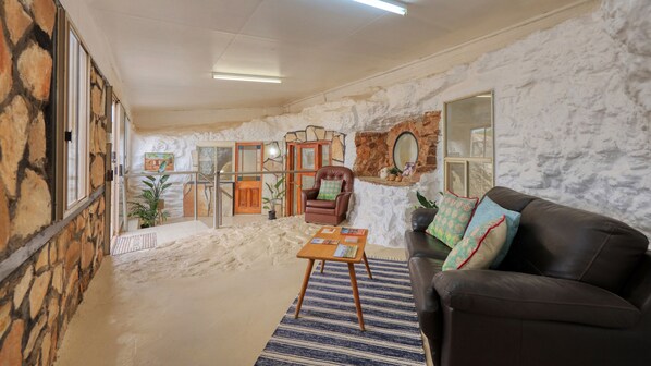 A cozy living area with a stone wall, a leather sofa, a coffee table, and a chair.