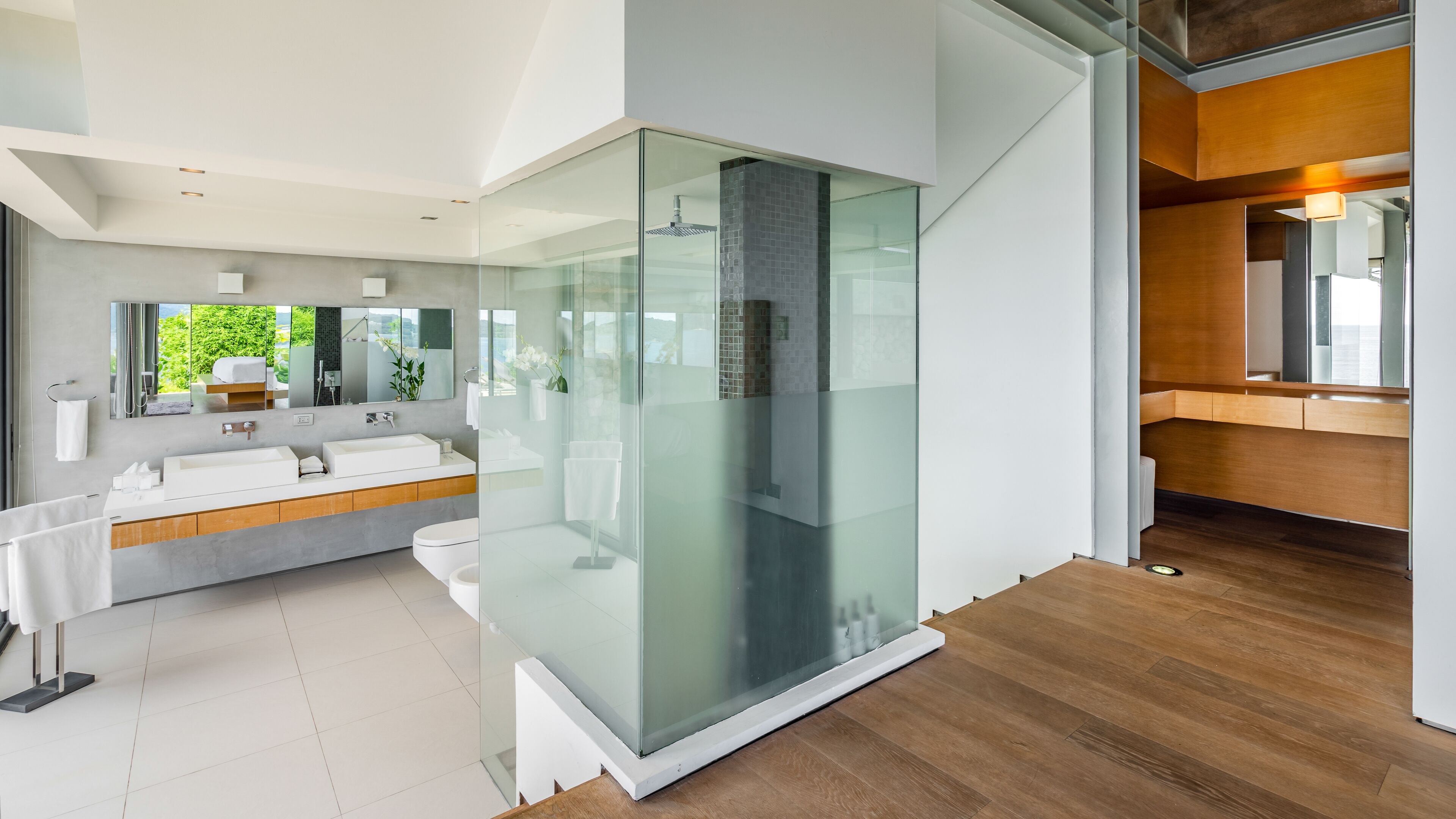 A modern bathroom with a glass-enclosed shower, a large vanity with a sink, and a mirror.