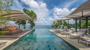 Una piscina al aire libre, sombrillas, sillones reclinables de piscina