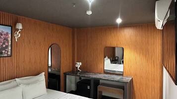 Una habitación de hotel con cama, escritorio, espejo y armario.