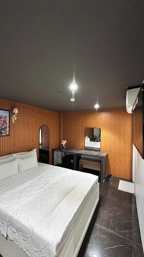A hotel room with a bed, a desk, a mirror, and a wardrobe. - Đông Như 3 (Ho Chi Minh City)
