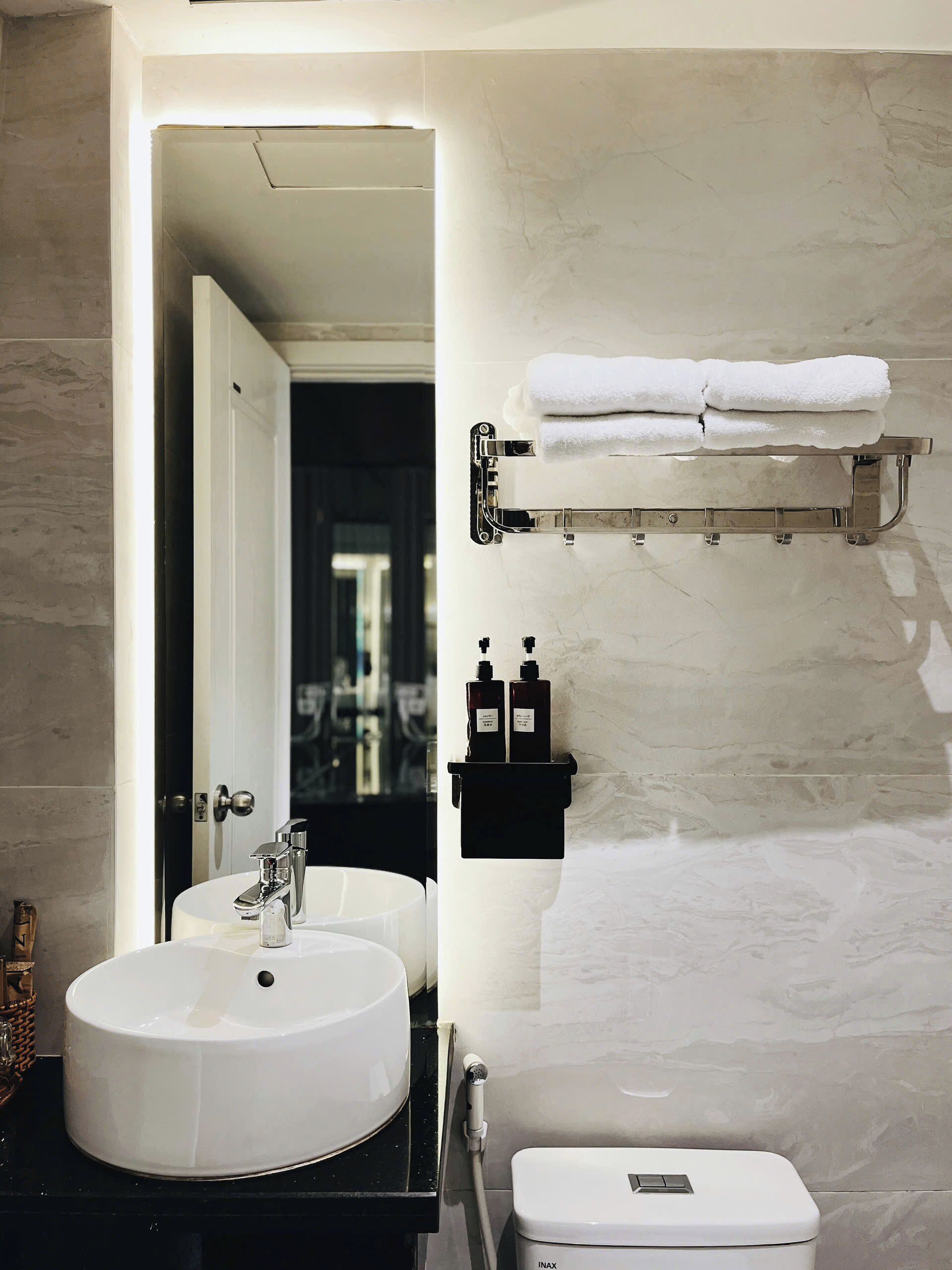 Un baño moderno con un lavamanos blanco, un inodoro y un perchero para toallas.