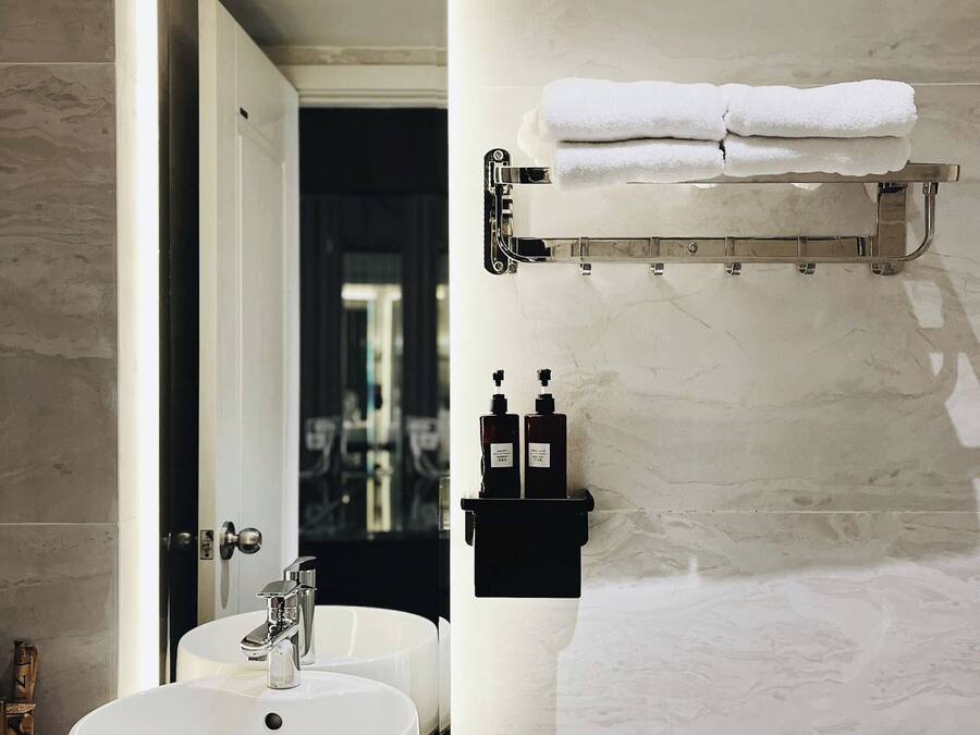 Un baño moderno con un lavamanos blanco, un inodoro y un perchero para toallas.