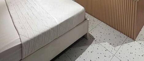 Ein modernes Hotelzimmer mit einem Bett, einem flachbildfernseher an der Wand und einer Schiebeglastür zum Badezimmer.
